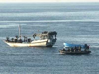 The revolutionary step taken by Somali pirates in or around 2009 was to marry the attack skiff to a larger fishing boat. The dhow, a traditional form of long distance fishing boat that has been used in the region for thousands of years, can tow a couple of attack boats further out to sea than where any small boat by itself ever could go, because of the wind and wave. The larger fishing boat can also carry more fuel and supplies for longer hunting missions. In this way, Somalis were able to break out from the Gulf of Aden and avoid the growing warship presence and begin threatening the waters off of Oman, western India and even the Maldives. This dhow is being stopped by a naval patrol, and is towing a whaler, a shorter fibreglass boat that Somali pirates equally like. Note the blue paint job given the whaler, so she can sneak up on her prey - and we don't mean fish in the ocean.